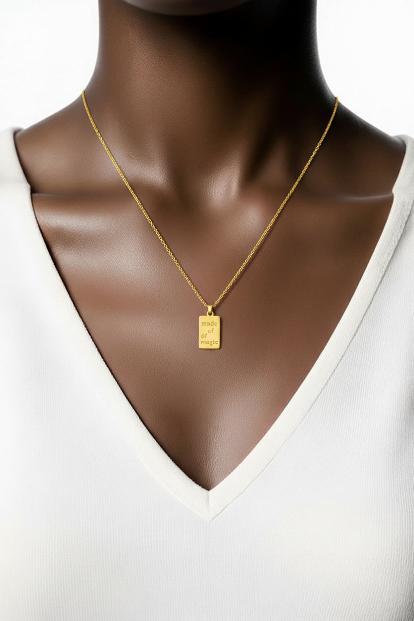 Gold necklace with a rectangular pendant on a mannequin wearing a white top.